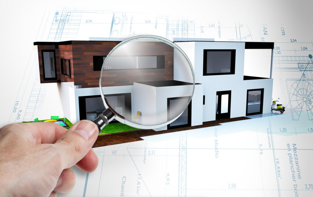 Zdjęcie budynku z lupą prześwietlającą dom trzymaną przez rękę
